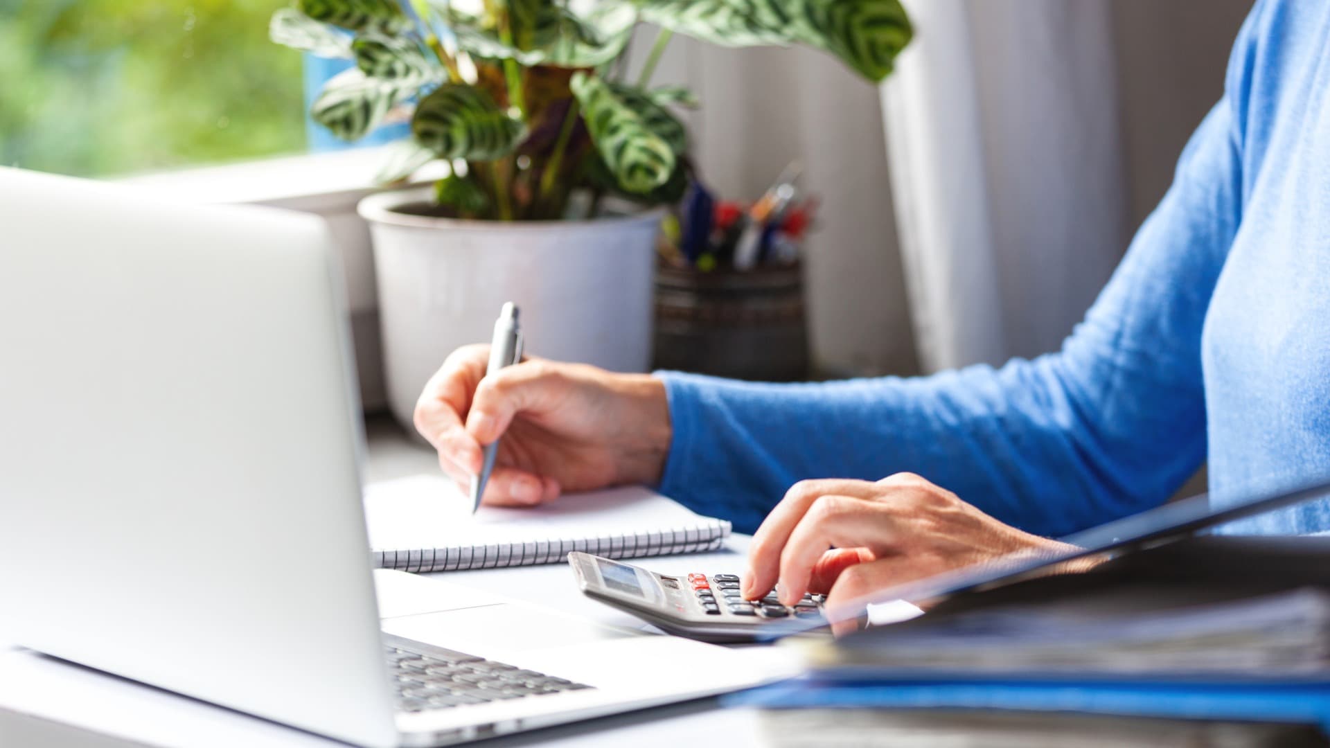 person plans move-in at destination on a laptop and calculates costs with a calculator