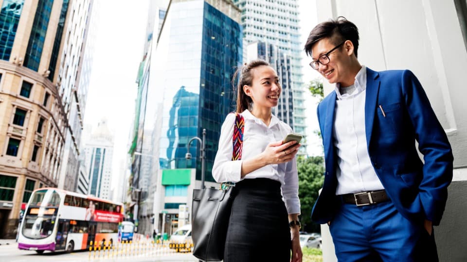 Eine Frau und ein Mann aus Singapur unterhalten sich auf der Straße über ihr Business