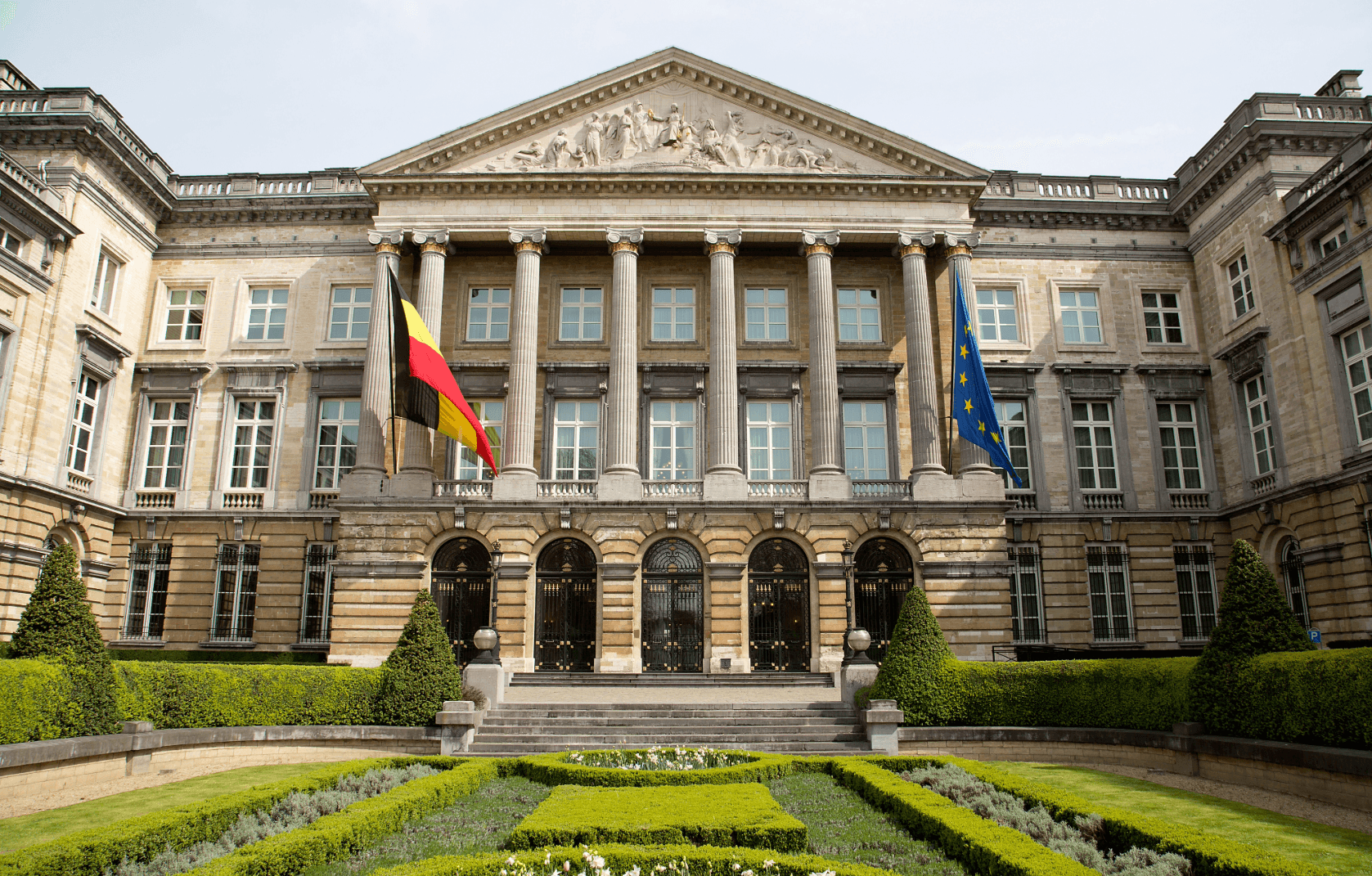 Historic government building in Brussels with Belgian and EU flags