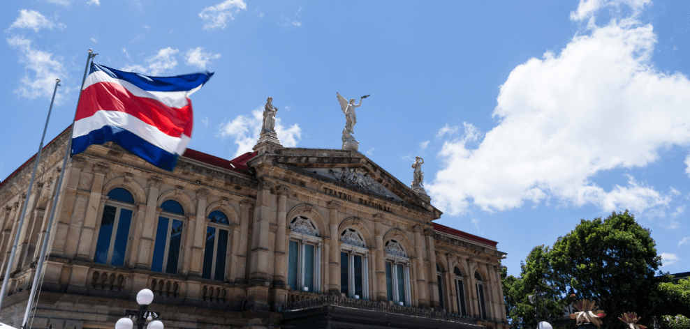 Flagge Costa Ricas vor historischem Theatergebäude unter blauem Himmel