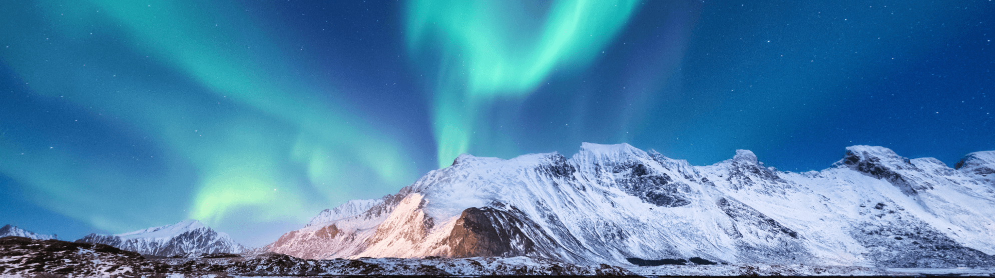 Northern lights over snow-covered mountains in Finland under a clear night sky