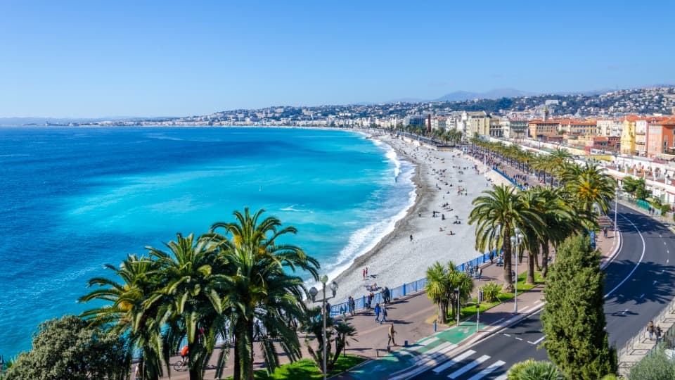 Mediterranean coast in Nice with beach, palm trees and blue sea