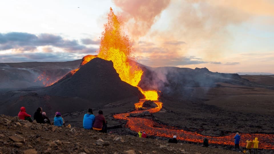 Volcanic eruption in Iceland with flowing lava and people watching from a safe distance