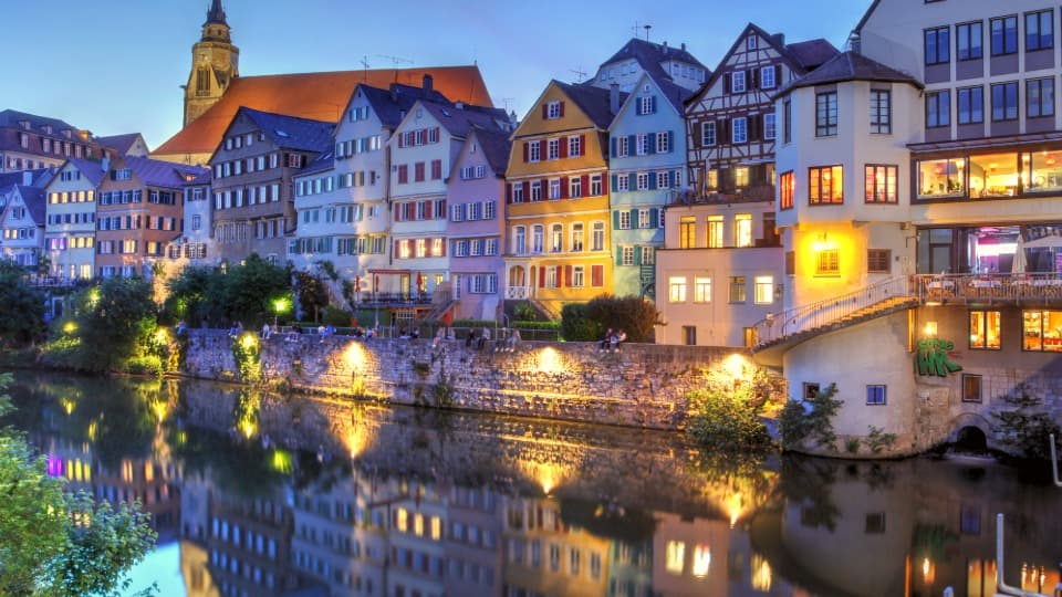Bunte Altstadthäuser am Fluss bei Abenddämmerung mit Spiegelung im Wasser