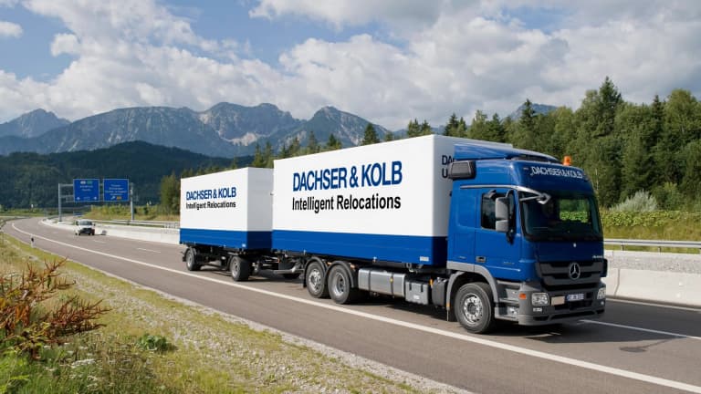 A blue DACHSER & KOLB moving truck and trailer transport household goods along the highway during a nationwide long-distance move.