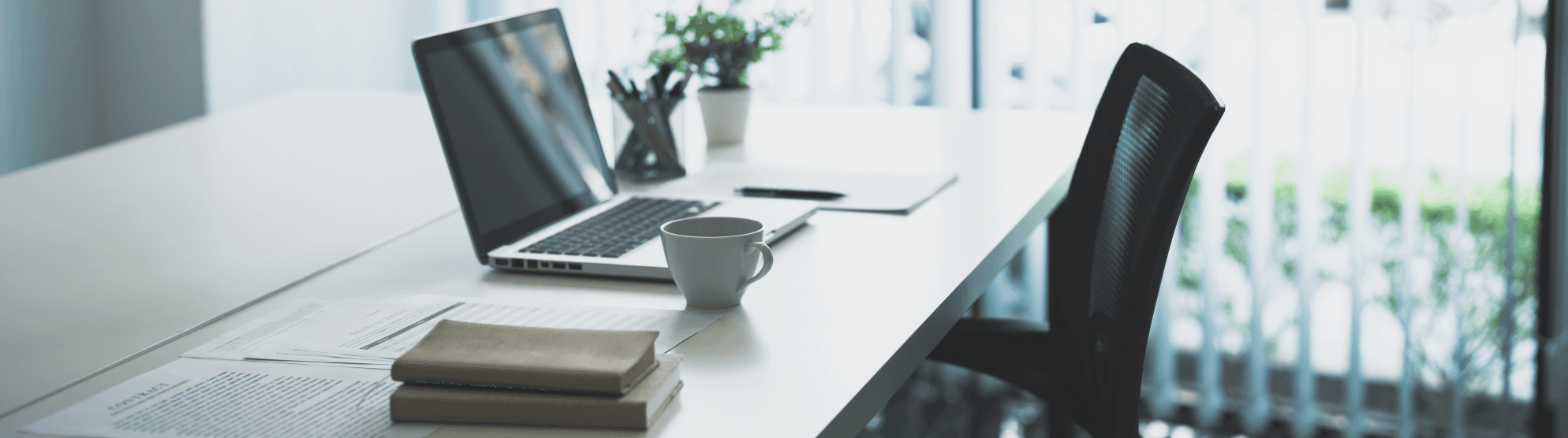 Bright home office workspace after moving with laptop, coffee mug, books, and chair. Setup ideas for modern working from home.