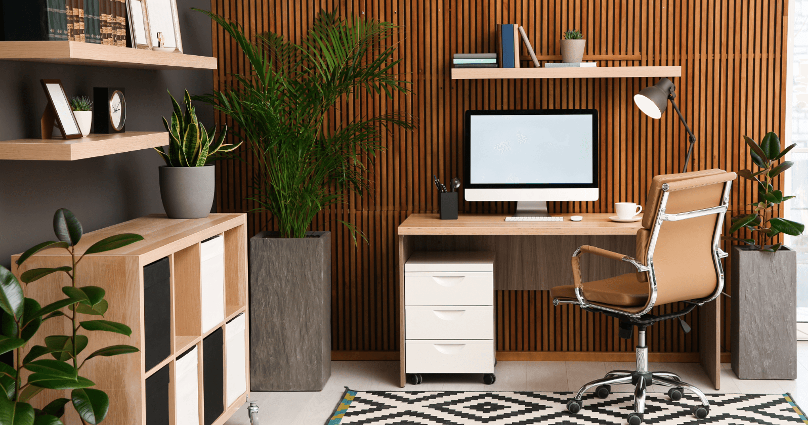 Modern home office after moving with wood paneling, desk, computer, office chair, and plants. Setup ideas for stylish working from home.