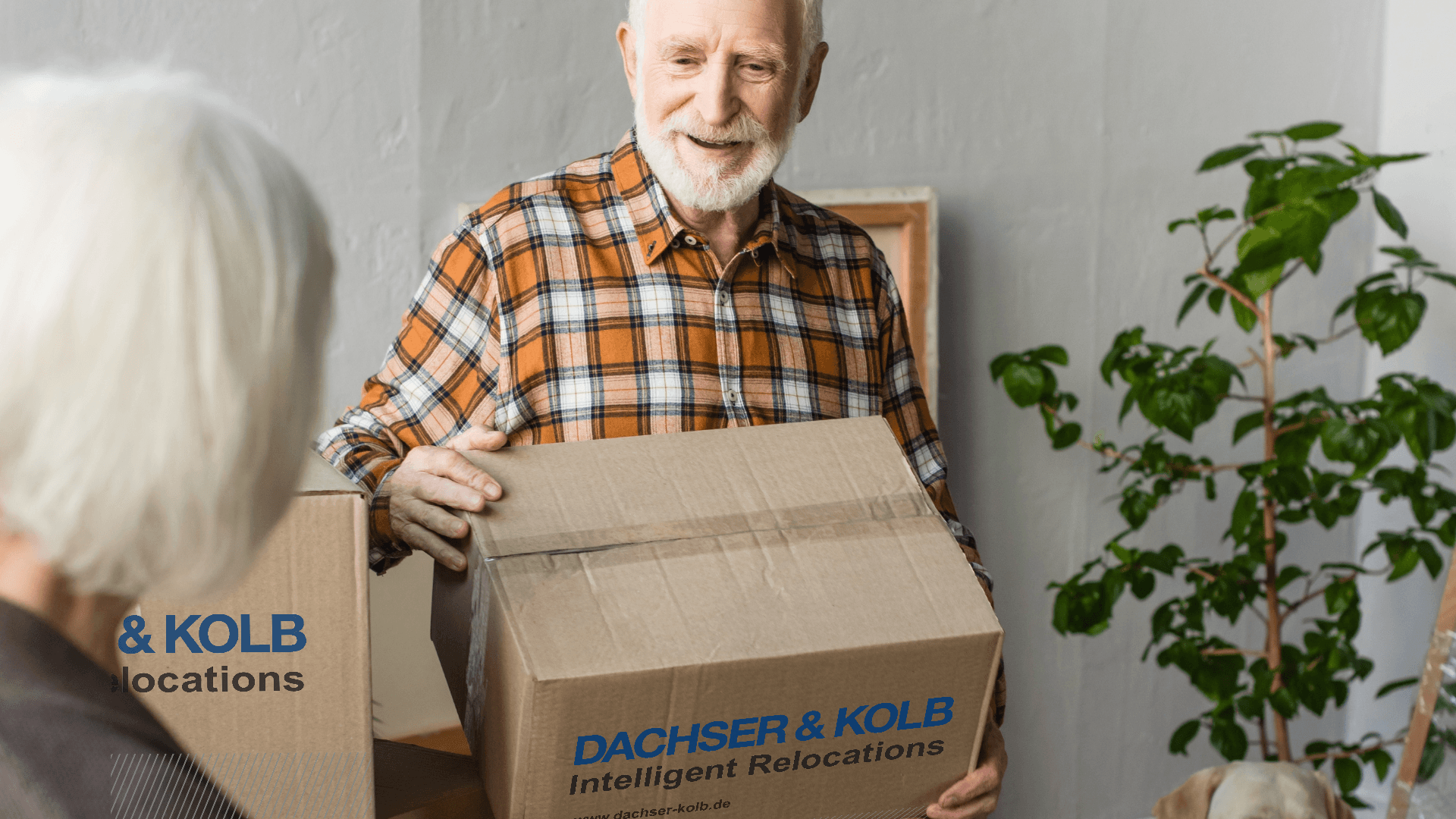 Senior man carrying moving box with DACHSER & KOLB – safe senior relocation to upscale residences