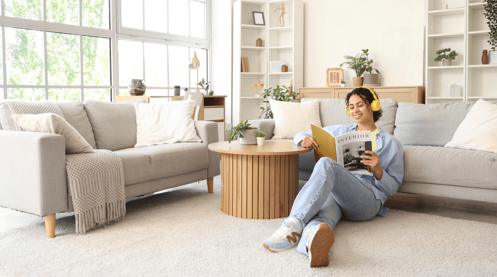 Woman with headphones reads magazine relaxed in new living room. Relaxation techniques for moving, finding peace.