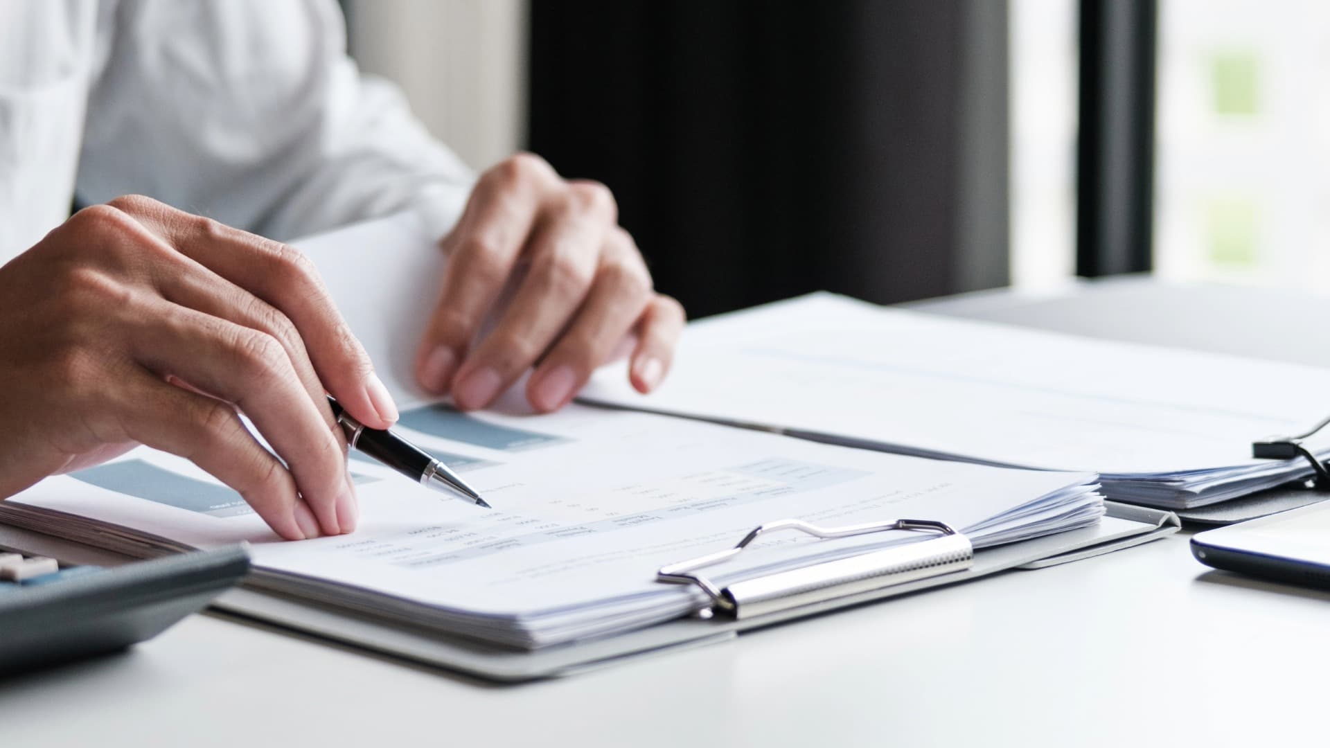 Person reviewing documents at a desk as a symbol of driving bans, permits and route planning