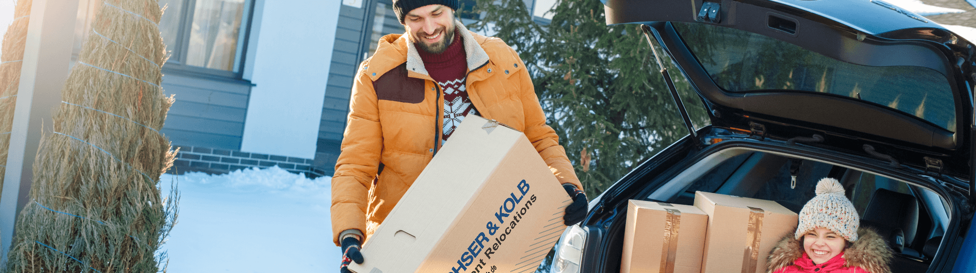 Vater und Kind beim Umzug im Winter – Umzugskartons werden bei Schnee ins neue Zuhause getragen
