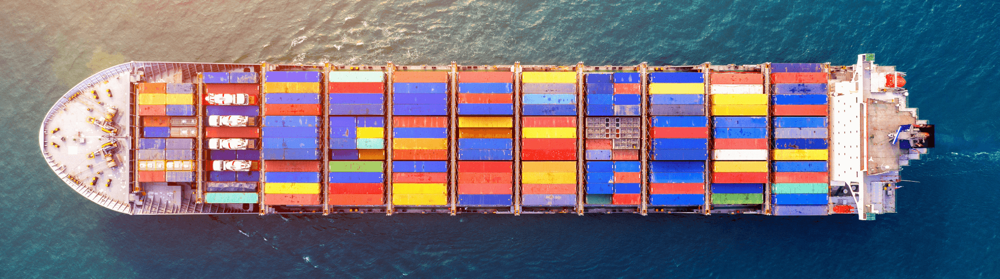 Drone shot of a huge cargo ship filled with colorful containers at sea. Represents Full Container Load (FCL).