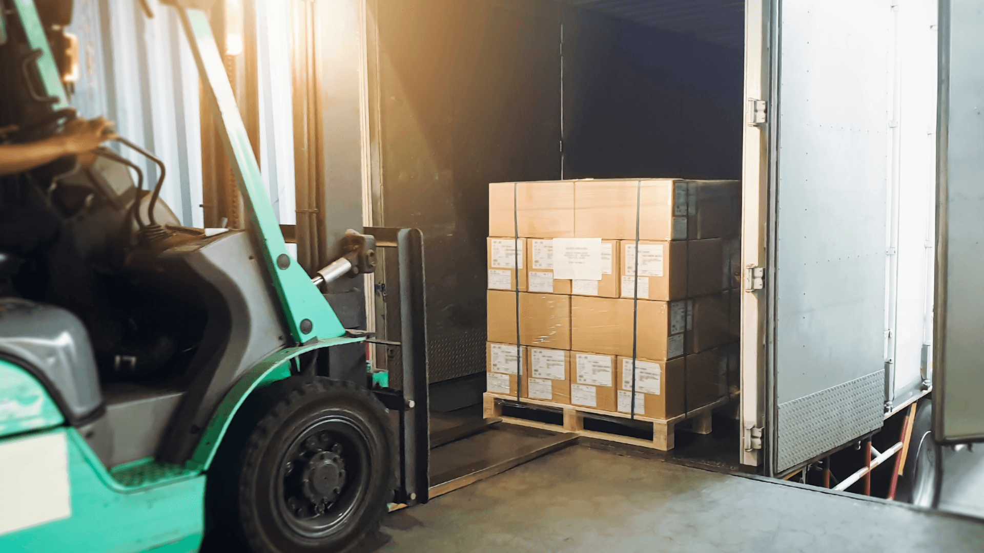 Forklift loading a truck with cardboard boxes on pallets. No wooden crates visible. Logistics and transportation.