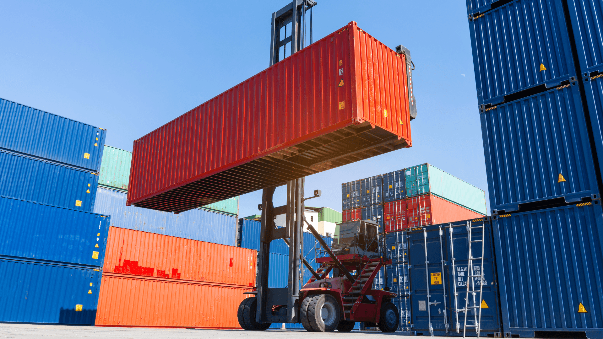 Gabelstapler hebt einen roten Überseecontainer. Verschiedene Containergrößen im Hintergrund. Logistik und Transport.