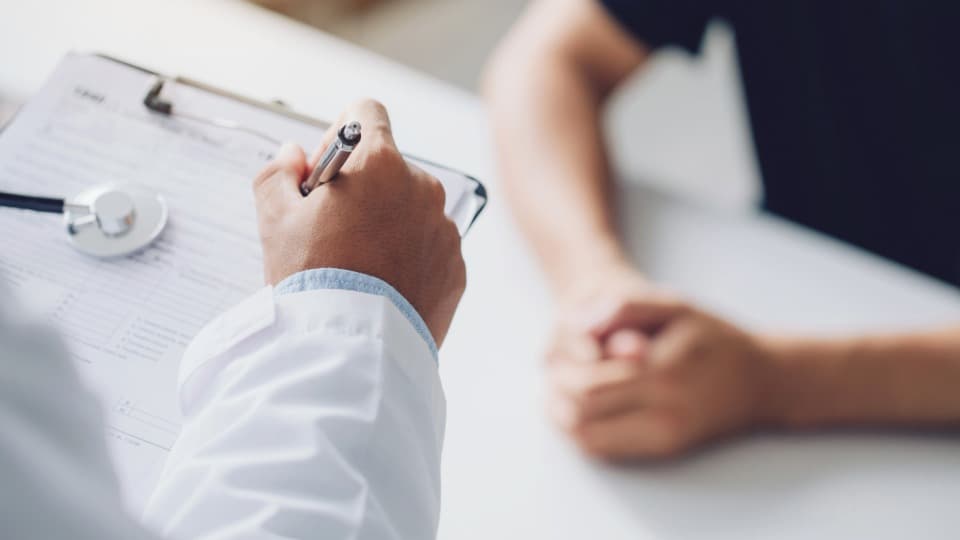 Ein chilenischer Arzt macht sich Notizen während eines Gesprächs mit einem Patienten