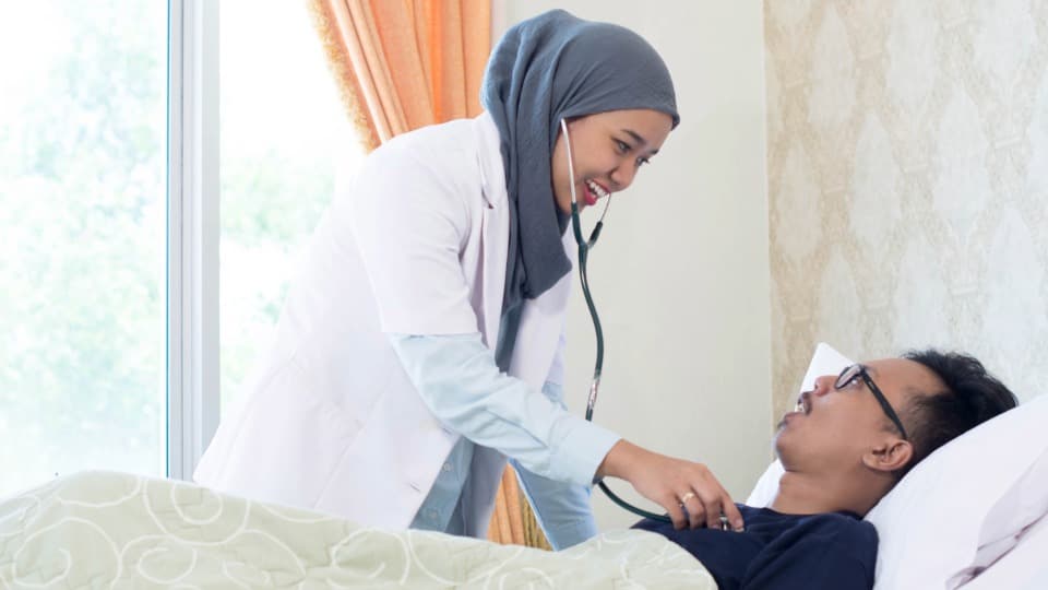 Eine malaysische Ärztin untersucht einen Patienten mit einem Stethoskop