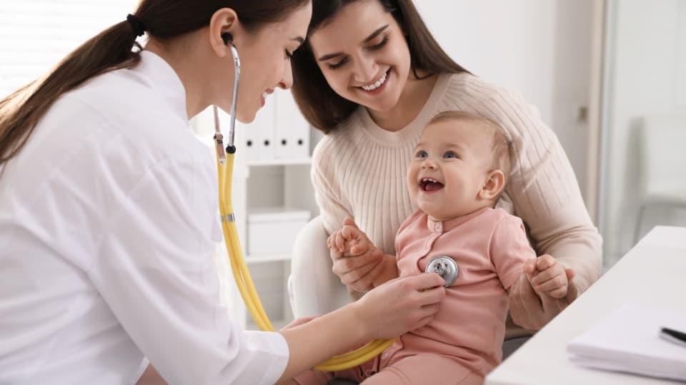 A Maltese doctor examines a toddler with a stethoscope during a routine checkup