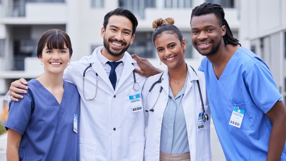 Four Portuguese doctors smile at the camera, arm in arm
