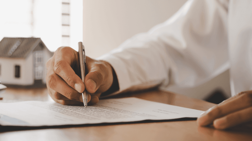Hand signing a lease agreement on the table