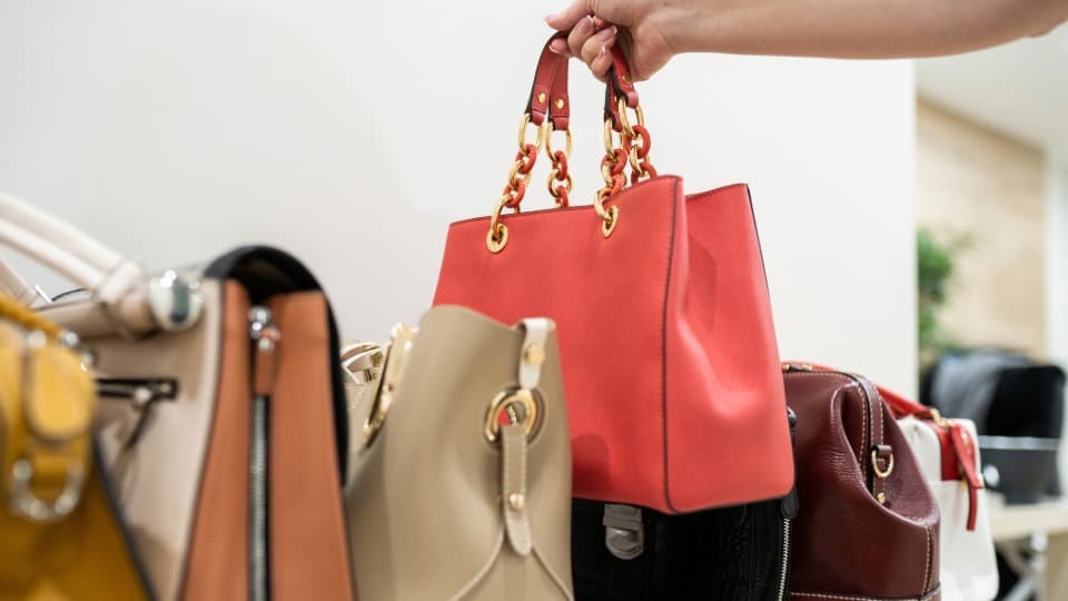 Eine Auswahl hochwertiger Handtaschen aus einer Kollektion, die für die systematische Zuordnung und den Umzug mit DACHSER & KOLB vorbereitet wird.