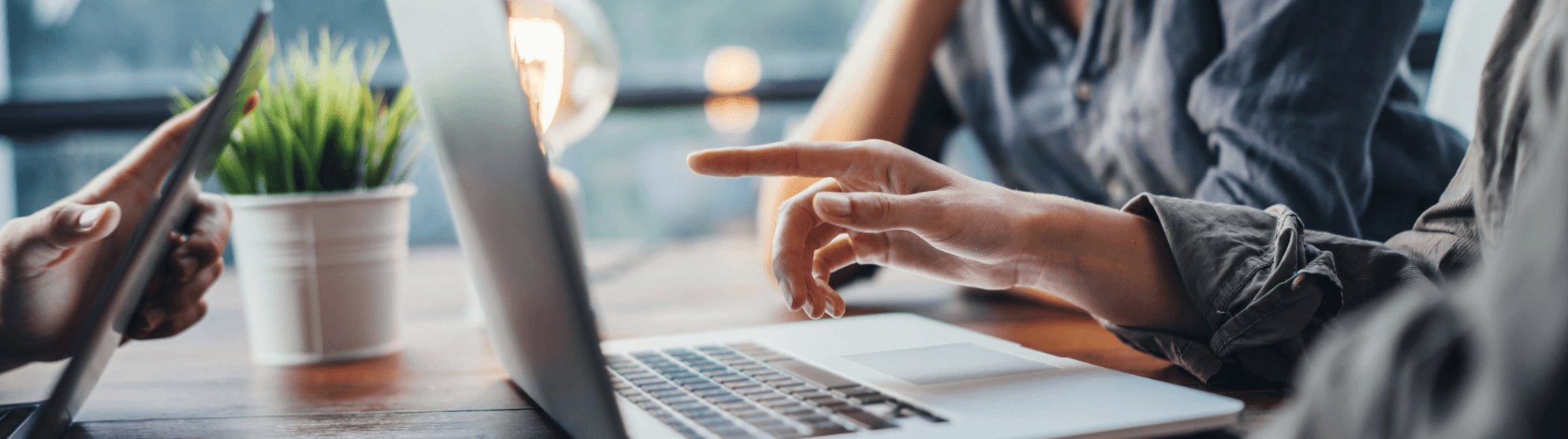 Hands pointing at a laptop during a discussion about career FAQs on a wooden table.