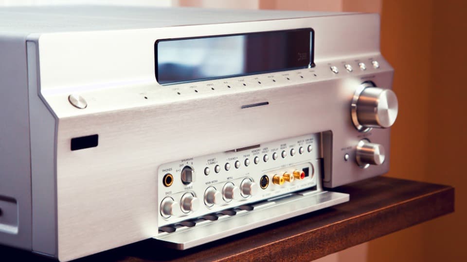Ein hochwertiger Hi-Fi-AV-Receiver aus Silber auf einem Holzregal vor dem fachgerechten Umzugstransport durch DACHSER & KOLB.