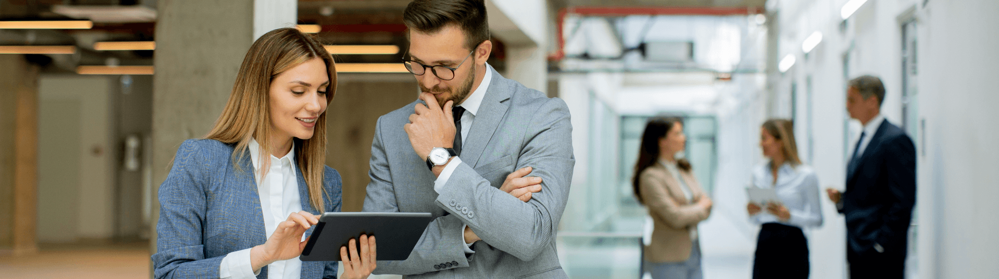 Two business professionals discussing career opportunities on a tablet in a modern office.
