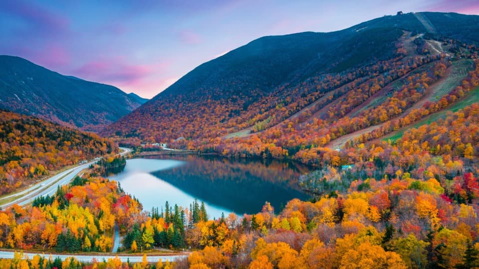 Landscape in the United States with a lake, mountains, and colorful mixed forest.