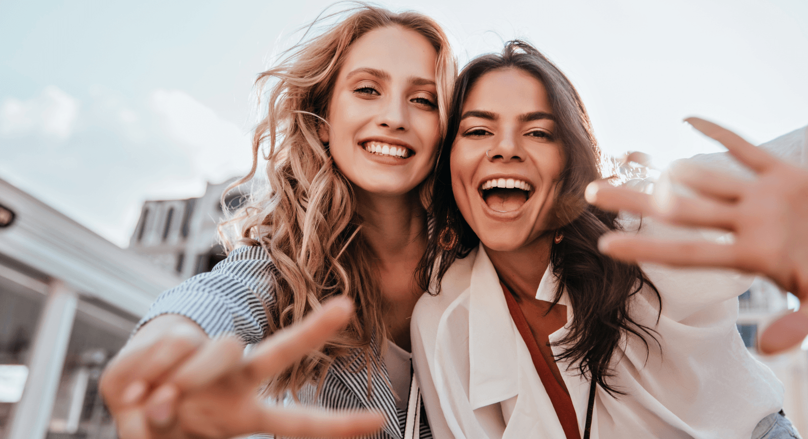 Zwei fröhliche junge Frauen machen ein Selfie im Freien. Nachbarschaft kennenlernen nach dem Umzug.