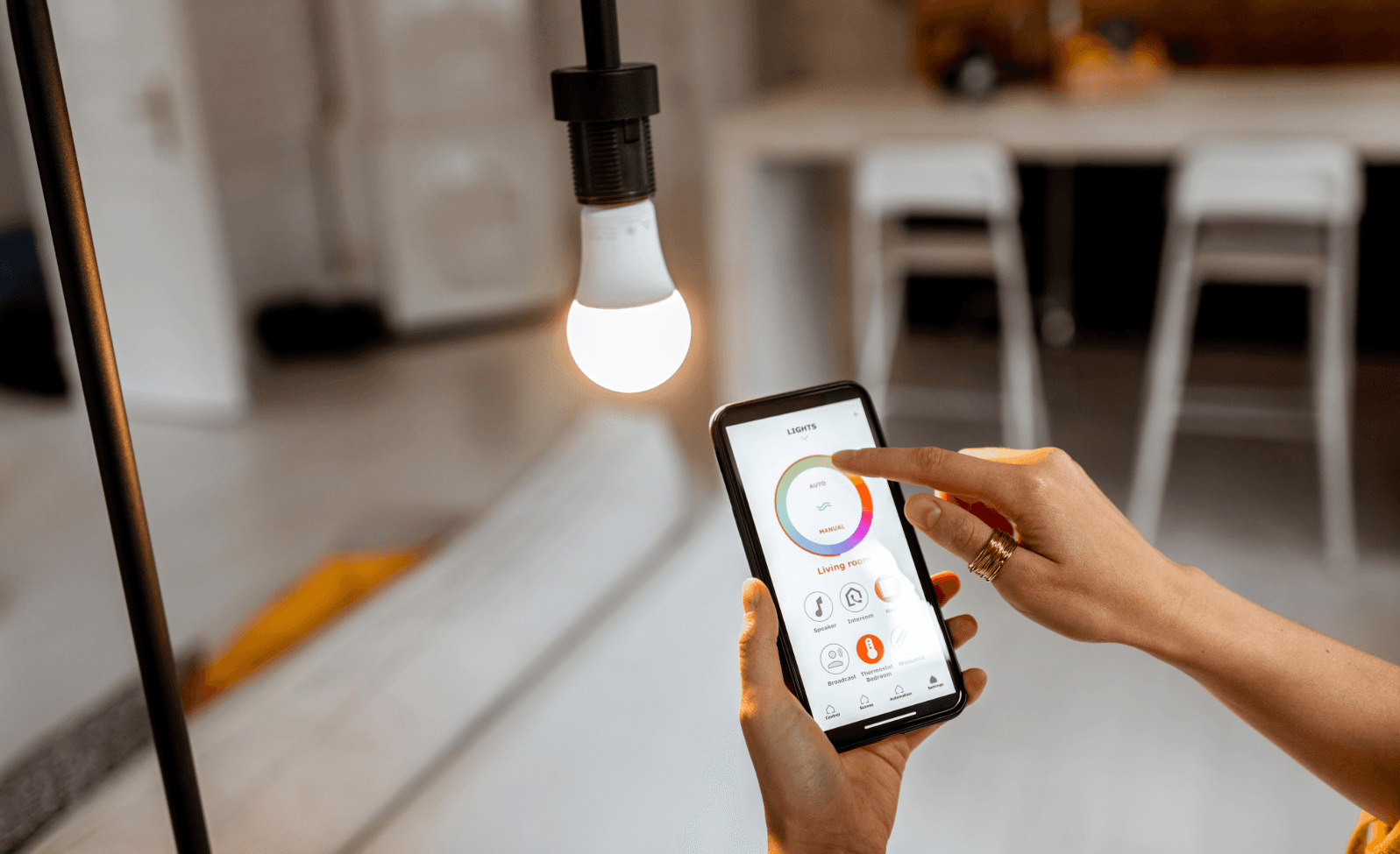 Smart-Home-Technologie: Person steuert Beleuchtung per Smartphone-App für mehr Komfort