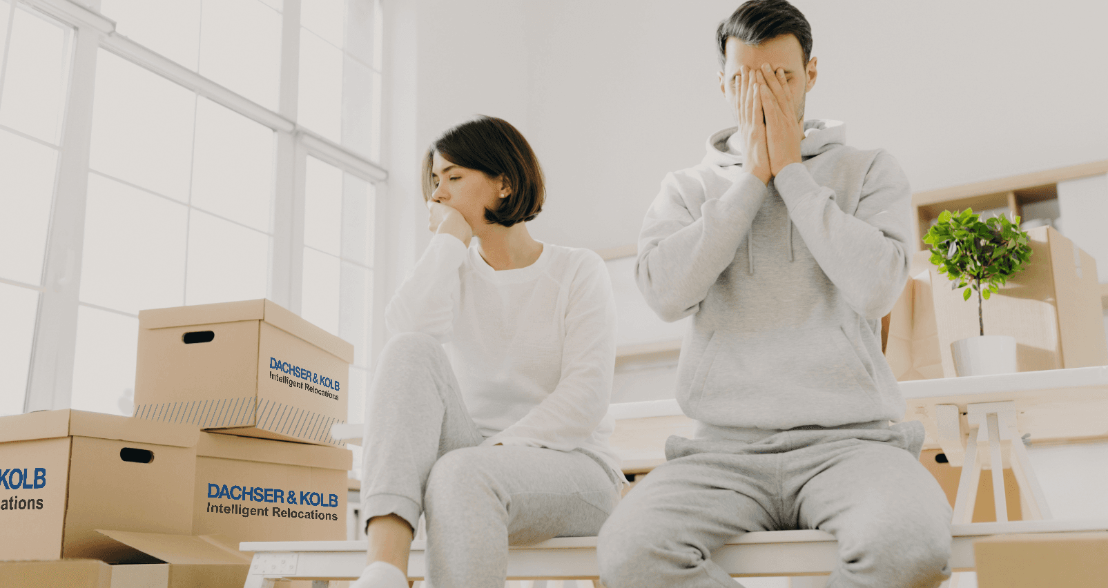 Exhausted couple sits amidst moving boxes. Stress management during relocation: Tiredness and frustration.