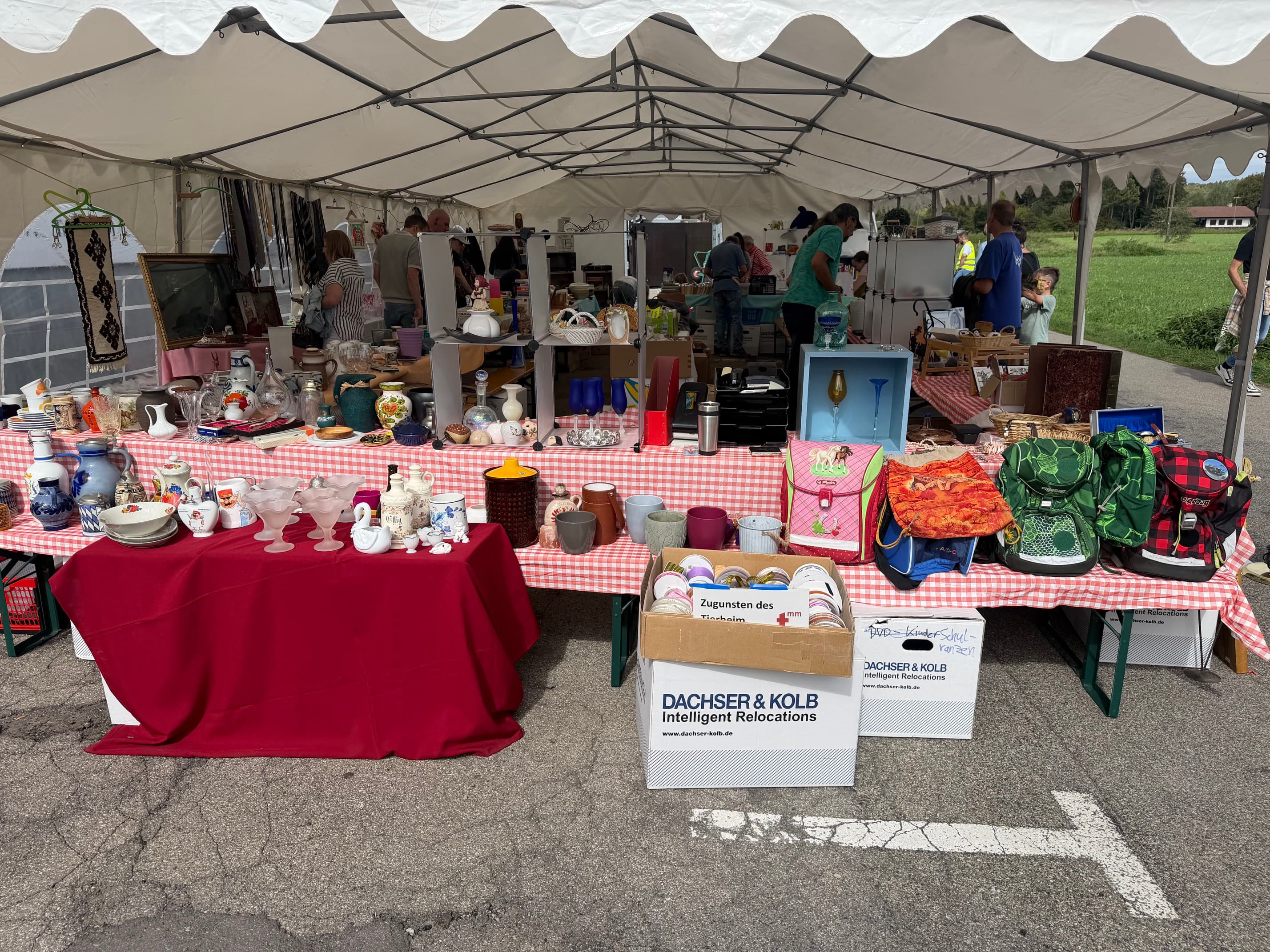Flohmarktstand mit Geschirr, Taschen und Umzugskartons von DACHSER & KOLB.