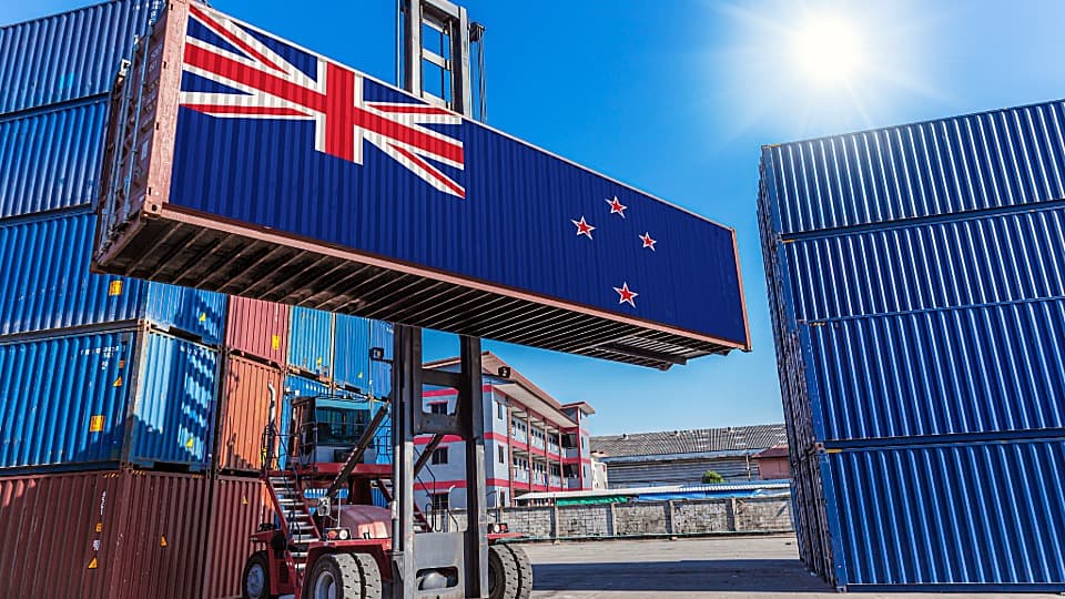 Ein Containerstapler verlädt einen Übersee-Container mit neuseeländischer Flagge für den Container-Umzug nach Neuseeland mit DACHSER & KOLB.