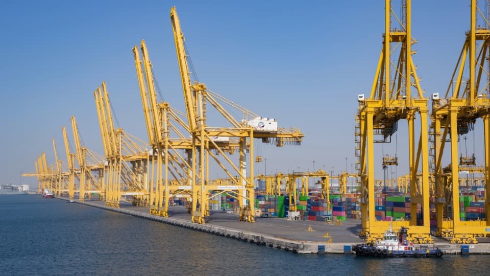 Large container port Jebel Ali in the UAE with yellow cranes and shipping containers for overseas moving with DACHSER & KOLB.