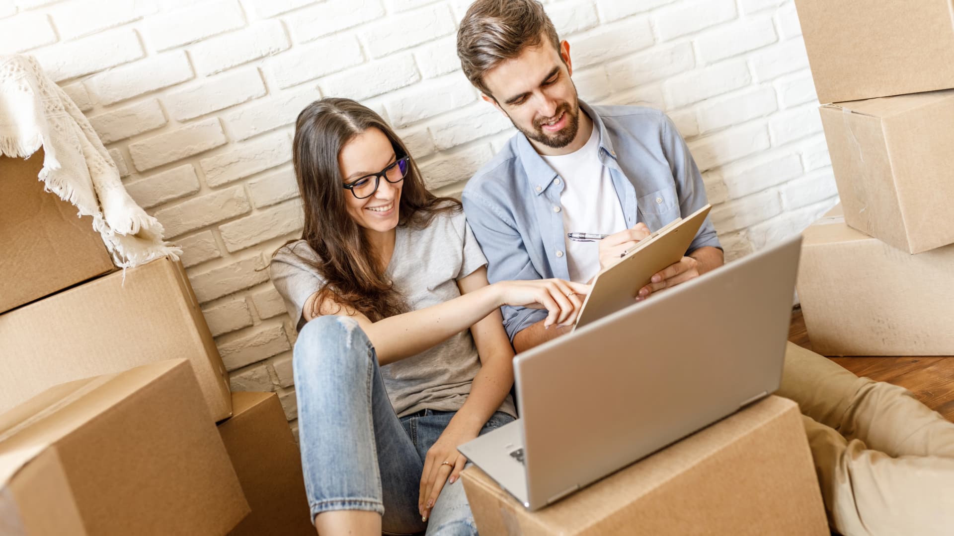 Young couple creating an inventory list on a laptop – planning and organizing for the move.