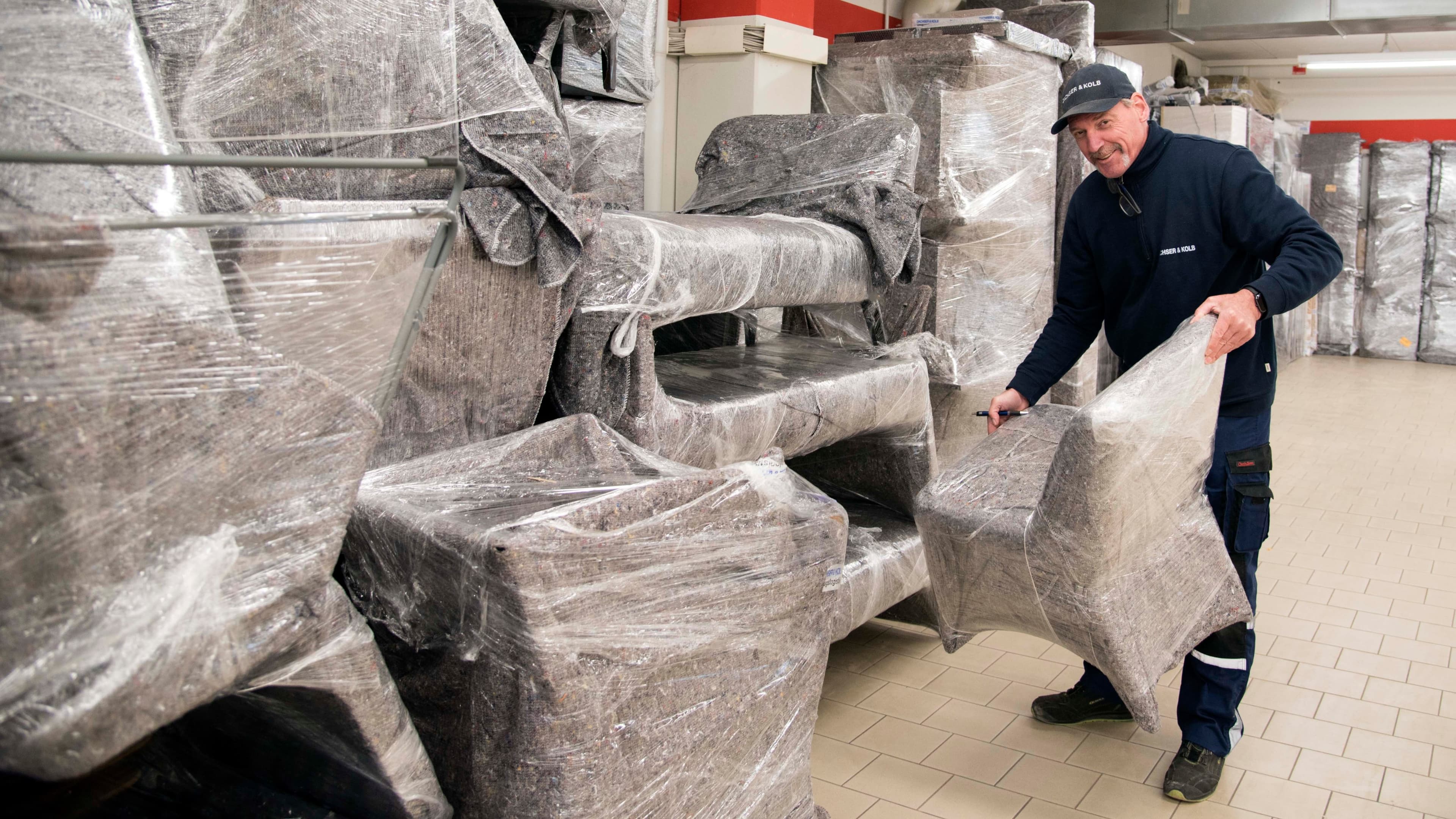Man carrying wrapped piece of furniture. Mover at work.