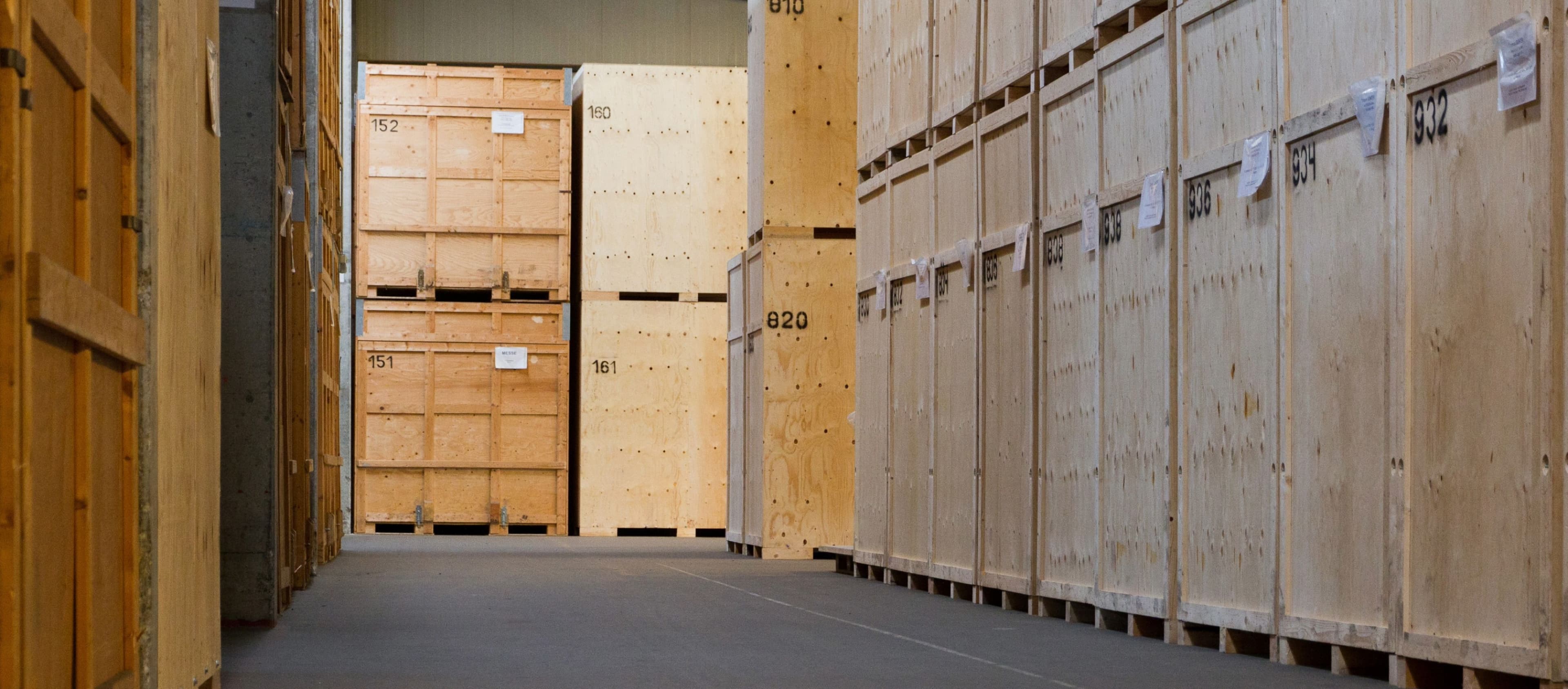 Row of numbered wooden crates in a secured moving warehouse for the safe storage of goods.