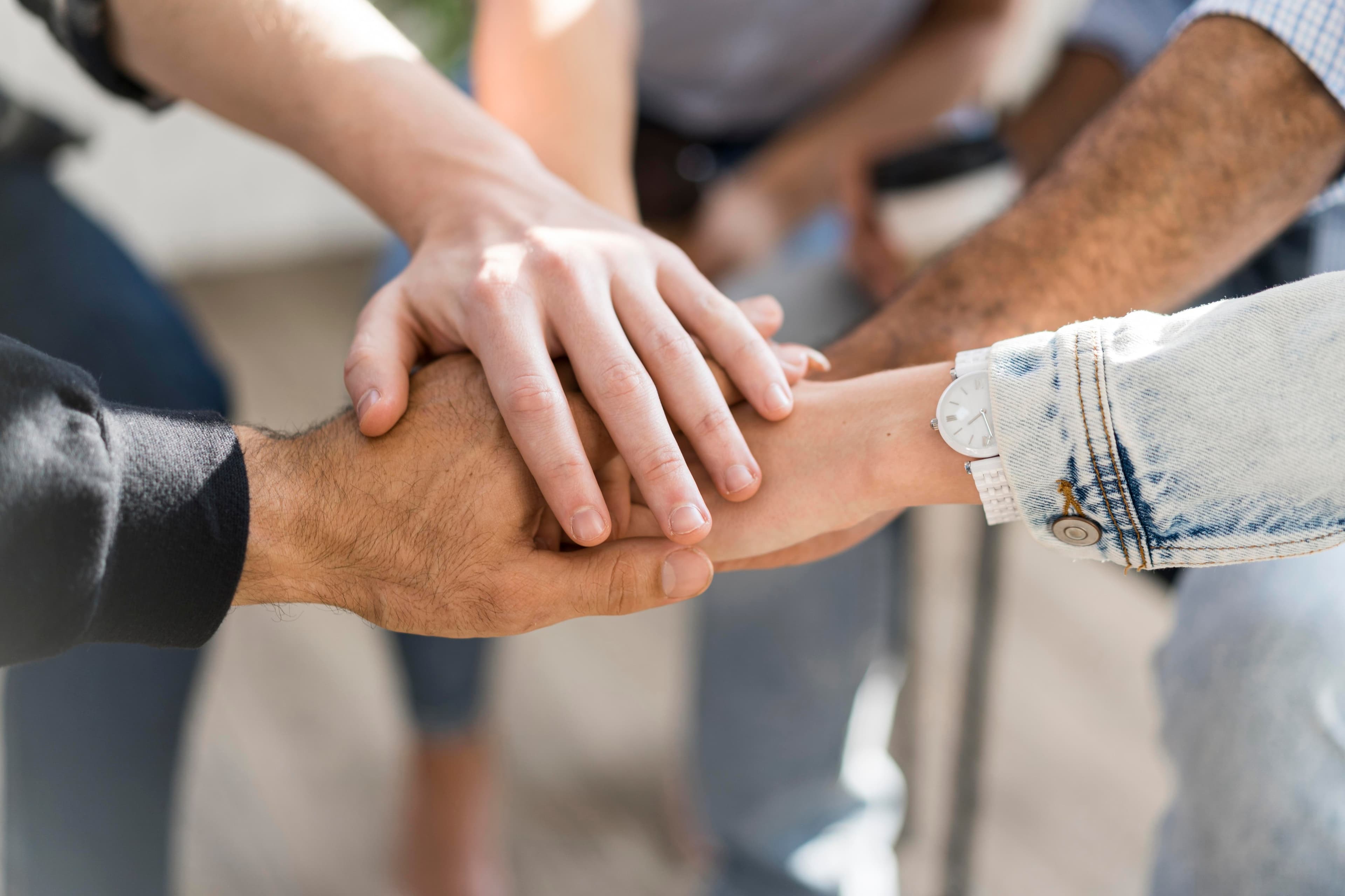 Verschiedene Hände übereinander als Symbol für Zusammenarbeit in unserem Partnernetzwerk.