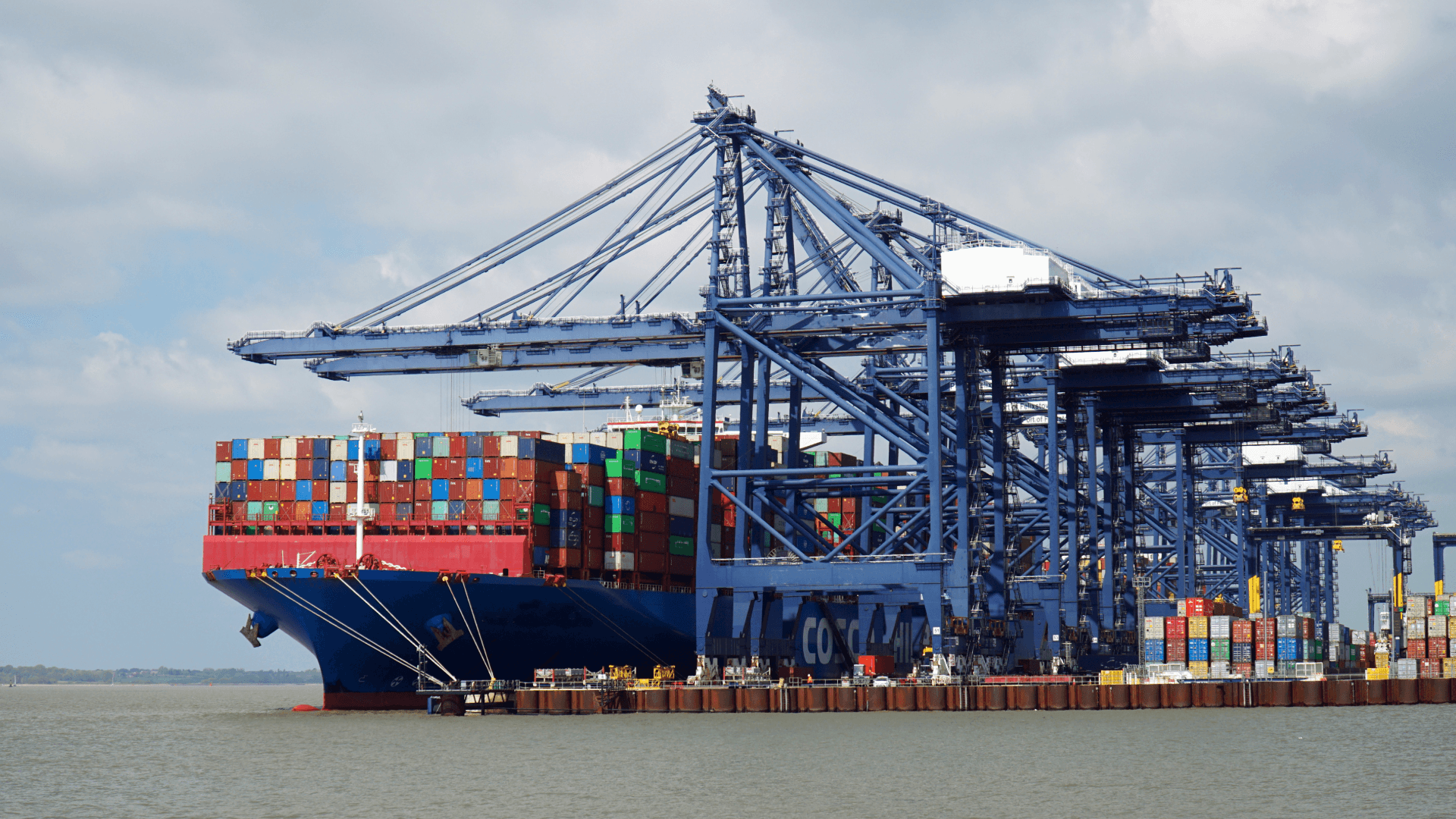 Container ship being loaded/unloaded in port, efficient logistics and ETD coordination at the terminal.