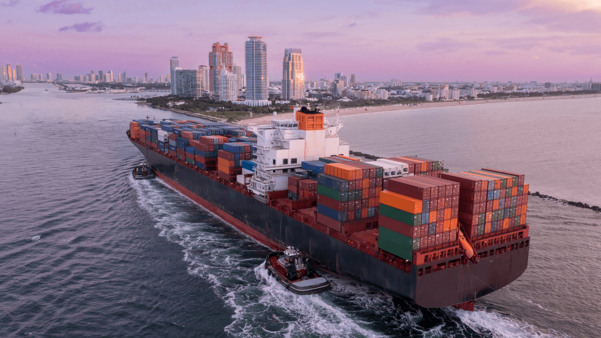 Container ship with tugboats entering a city port – experts for seamless sea freight removals worldwide.
