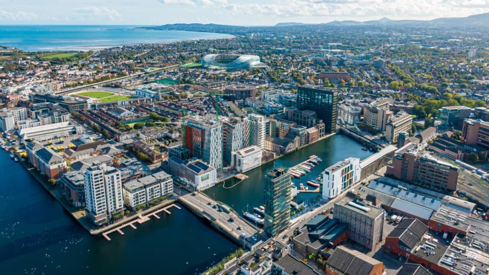 Aerial drone view of the Grand Canal Dock in Dublin with the Aviva Stadium in the background, a hub for Ireland's tech sector.