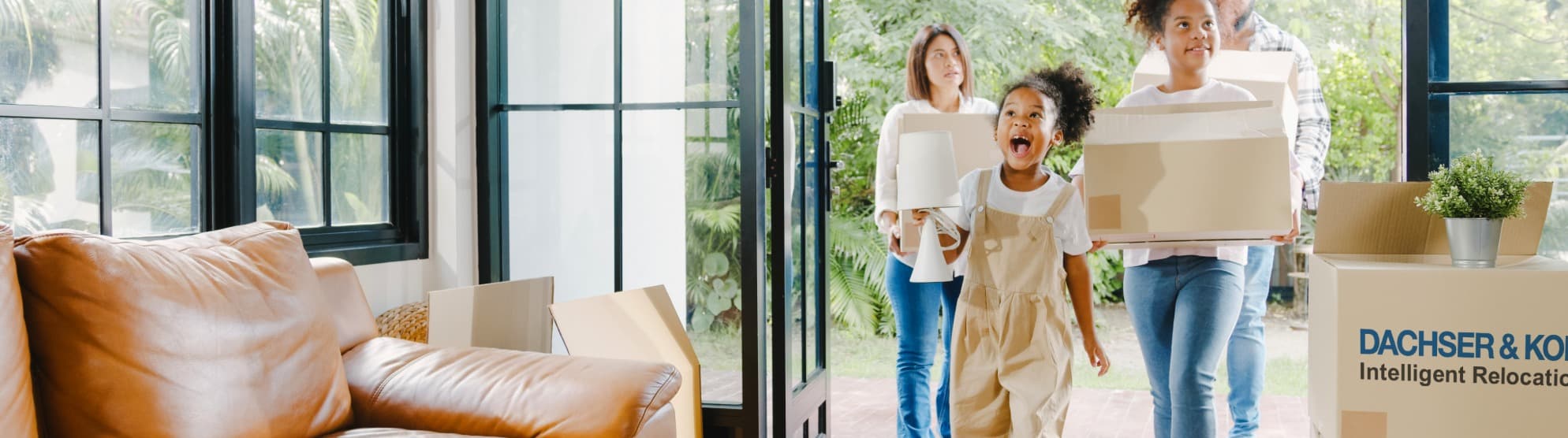 Family carrying moving boxes into new home – symbolic image for practical living tips