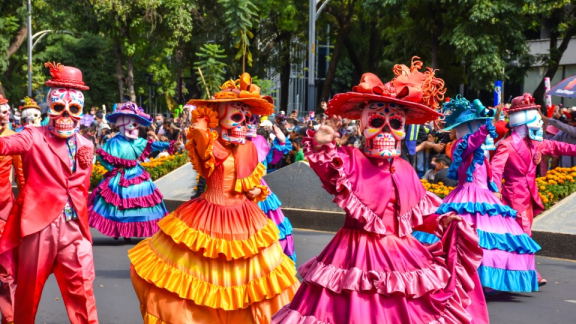 Costumed people wearing skull masks celebrate Día de Muertos in Mexico.