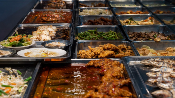 Hawker Culture in Singapore: A variety of dishes are lined up on a buffet in a communal dining area
