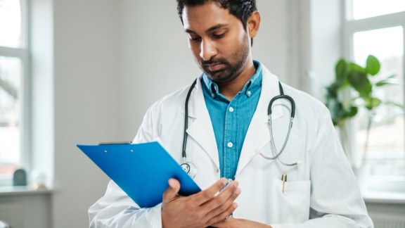 A doctor in Pakistan checks data on a clipboard