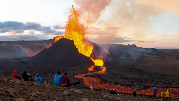 Volcanic eruption in Iceland with flowing lava and people watching from a safe distance