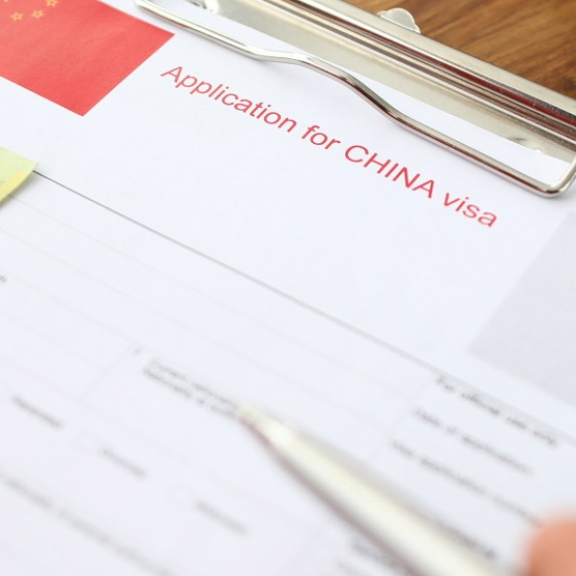Reisepass, Geldscheine und Visumantrag für China auf einem Schreibtisch