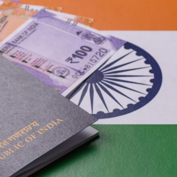 Indischer Reisepass mit Visaunterlagen und Rupien auf der Flagge Indiens
