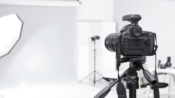Eine Kamera auf einem Stativ im Vordergrund eines Fotostudios zur Veranschaulichung der Transport-Entscheidung bei DACHSER & KOLB.