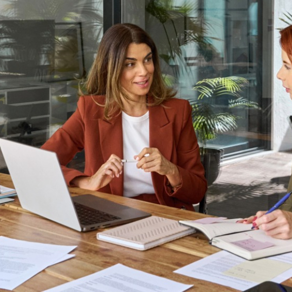 Global mobility consulting at DACHSER & KOLB – Two women discuss the planning of an employee assignment on a laptop in a modern office.